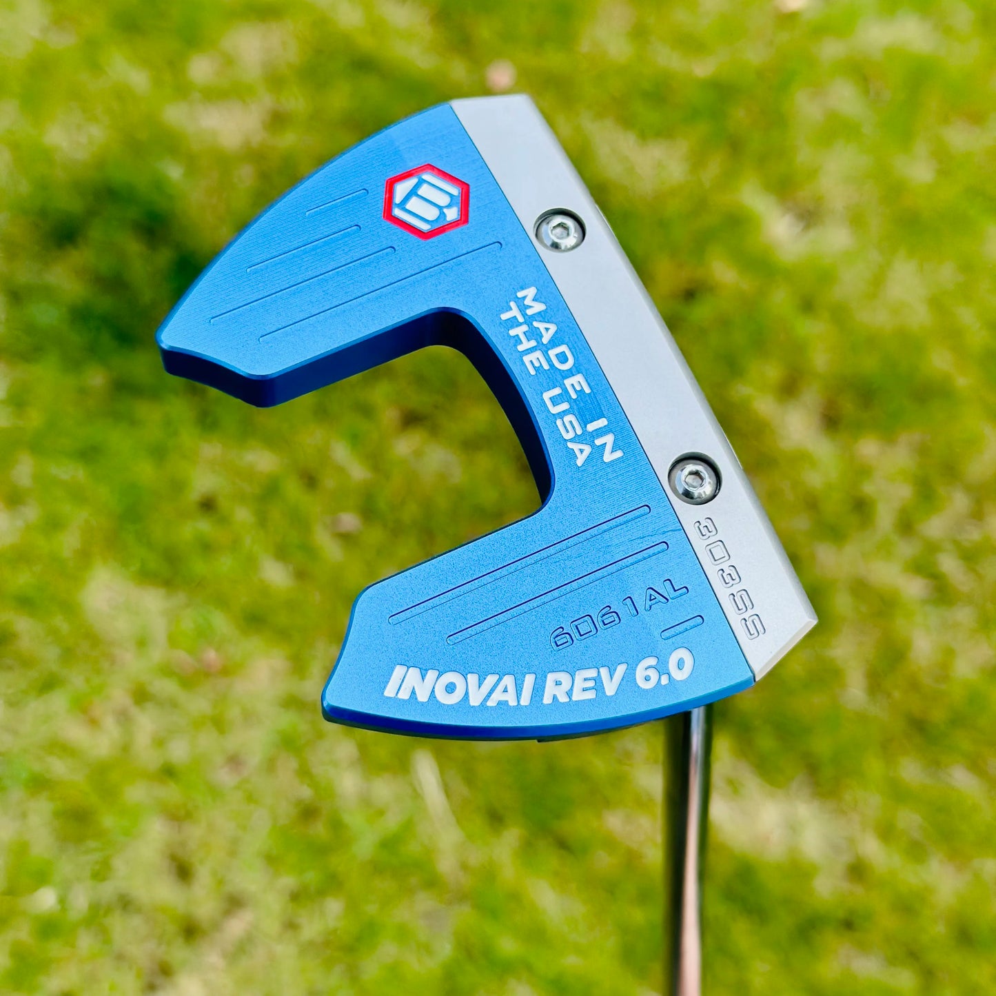 Blue golf putter head with 'Made in USA' and 'INOVAI REV 6.0' branding on a grass background