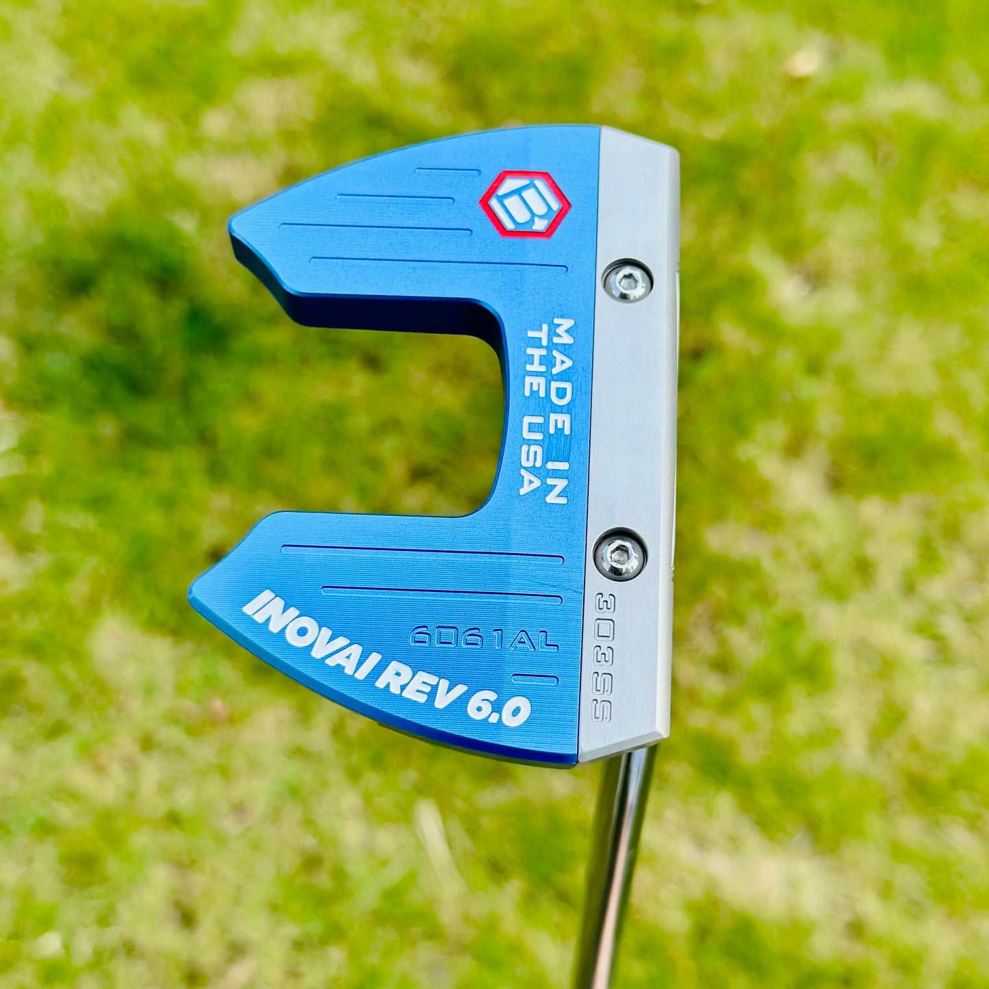 Blue golf putter head with 'Made in USA' and brand logo on a grass background