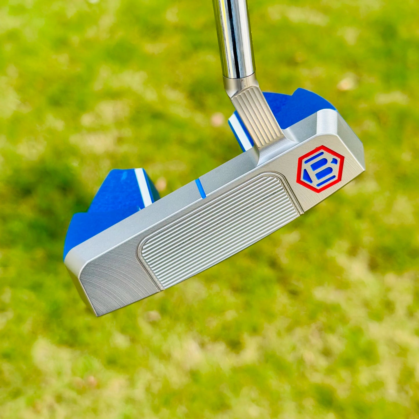 Golf putter with a blue and silver design on a grass background